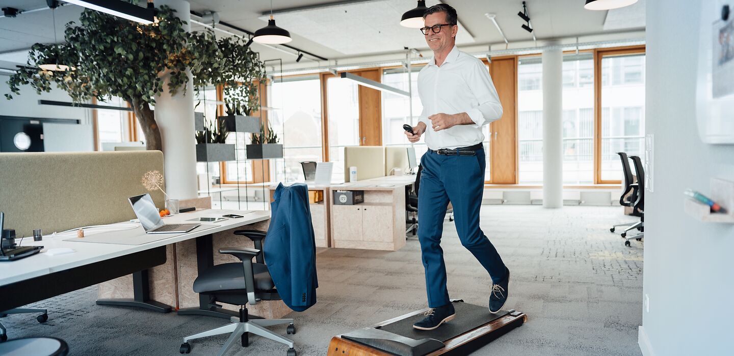 Mann läuft im Büro auf einem Laufband