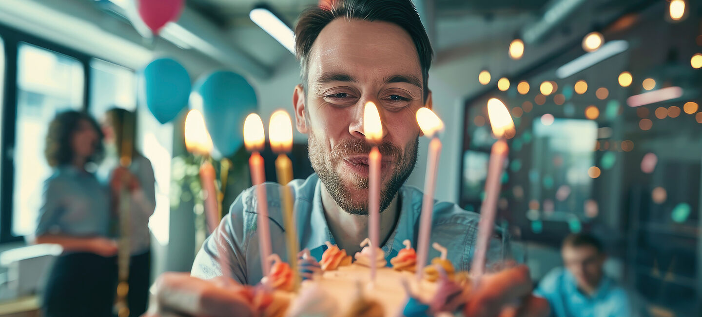 Mann bläst Kerzen auf einer Torte aus