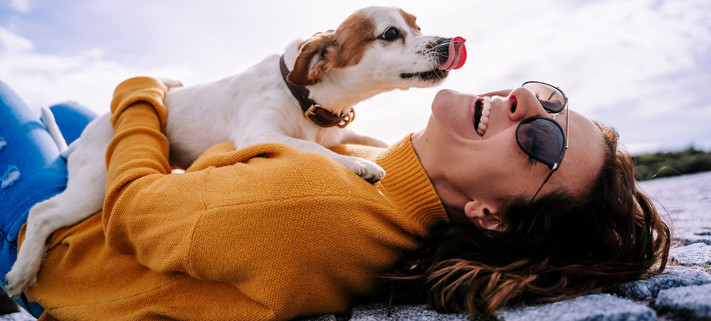 Eine Frau spielt mit einem Hund im Freien.